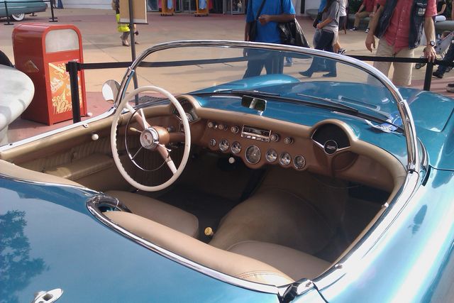 Blue convertible car interior with tan seats and dashboard, white steering wheel, and multiple gauges