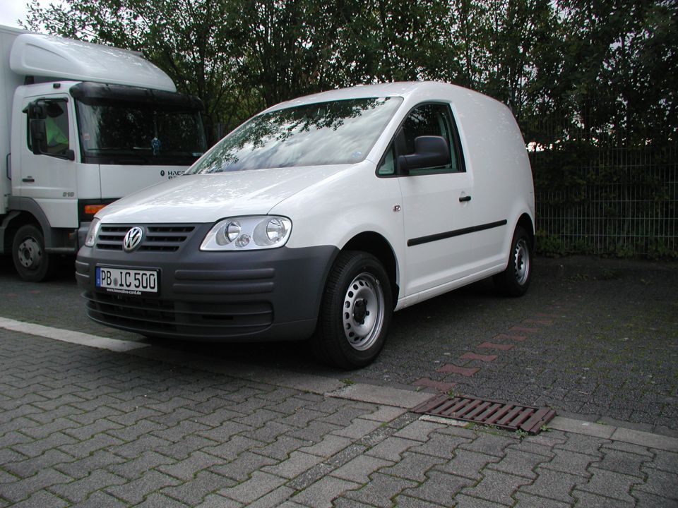 White Volkswagen Caddy panel van with steel wheels and German plates, front three-quarter view