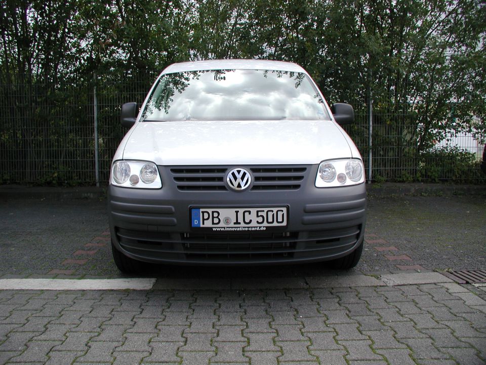 Silver Volkswagen Caddy van front view with German license plate on paving stones