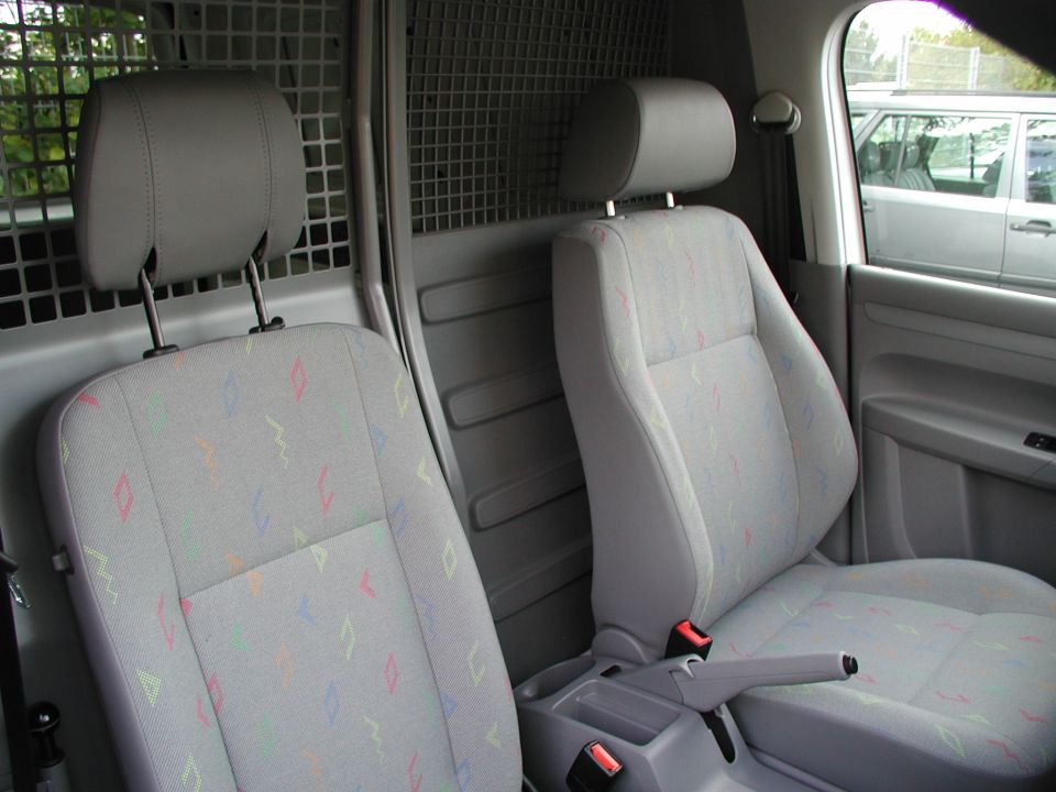 Panel van cab interior with patterned gray cloth seats and mesh cargo bulkhead