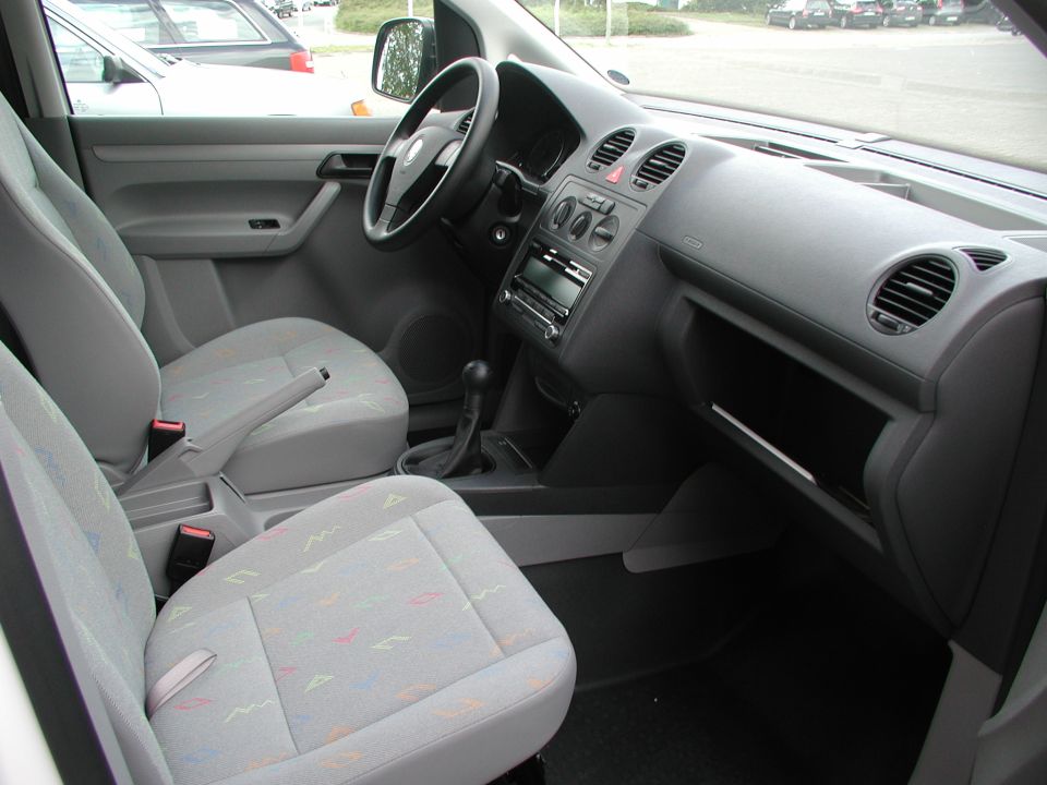 Gray cloth interior of a car with manual shifter and dashboard controls