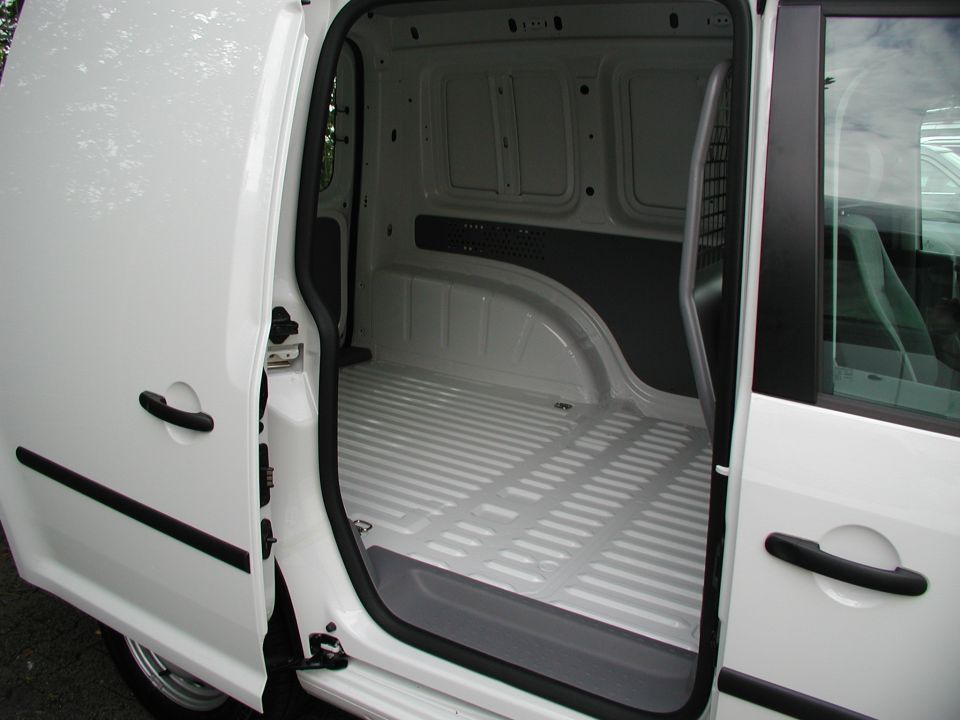 Open sliding door of a white panel van revealing an empty ribbed cargo floor and mesh bulkhead