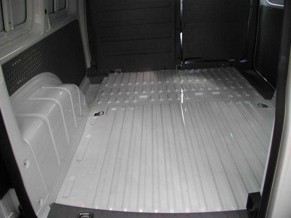 Empty white ribbed-steel cargo floor and tie-down points inside a panel van