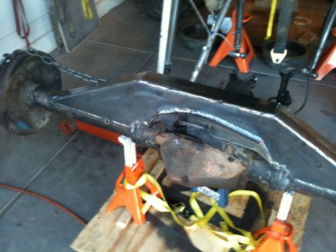 1966 Ford Bronco - Close-up of a vehicle's rear axle assembly, supported by jack stands and a wooden pallet.