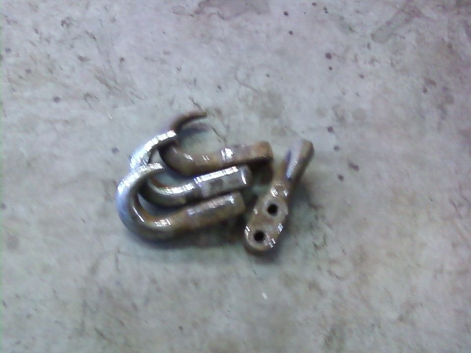 Three metal tow hooks and one bracket on a concrete surface