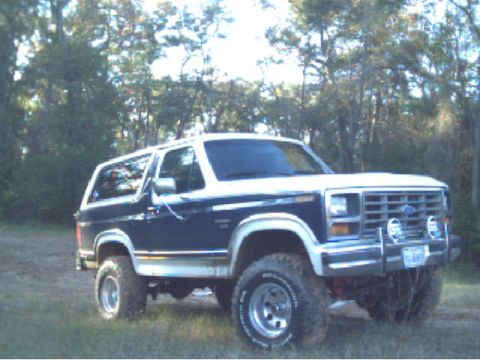 1986 Ford Bronco - This 1986 Ford Bronco is shown from a 3/4 front angle, parked in a grassy, wooded area.