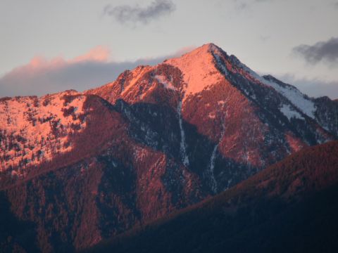 2006 Ford E350 - The sun casts a warm glow on the snow-capped mountains, highlighting the terrain.
