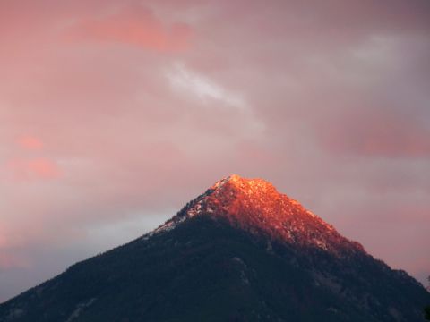 2006 Ford E350 - A mountain peak glows with orange light from the setting sun, set against a backdrop of soft pink clouds.