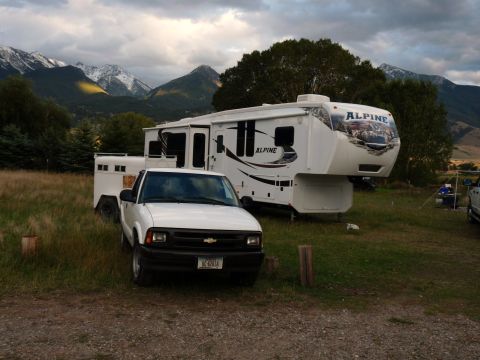 2006 Ford E350 - A white pickup truck is parked in front of a large RV and horse trailer, with mountains in the background.