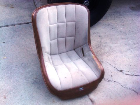 1986 Ford Bronco - A single bucket seat with a quilted pattern and brown trim is shown outdoors on a concrete surface.