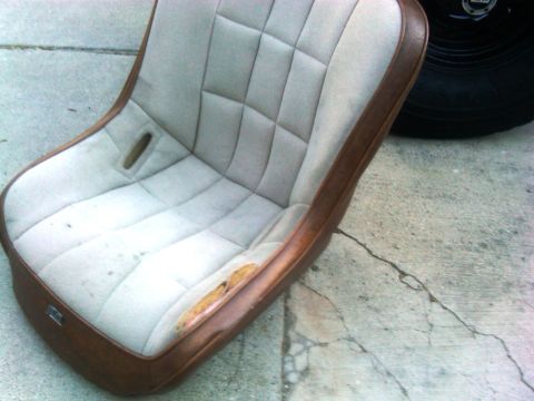 1986 Ford Bronco - A worn car seat with a diamond-stitched pattern is shown on a concrete surface.