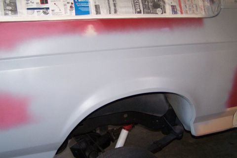 1990 Ford Bronco - A 1990 Ford Bronco fender is prepped for paint, with red primer visible around the wheel well.