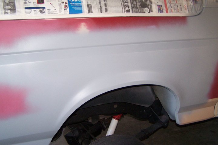 Gray 1990 Ford Bronco fender with red primer spray, showing wheel well and suspension