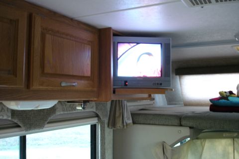 2005 Chevrolet Silverado 3500 - Interior view of an RV, showing cabinets, a television, and a sleeping area.