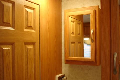 2005 Chevrolet Silverado 3500 - Interior view showing wood paneling, a door, and a mirrored medicine cabinet reflecting another door and room.