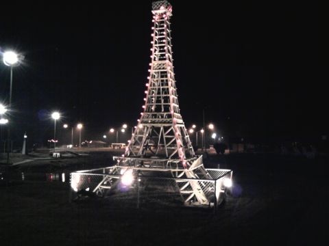 2005 Chevrolet Silverado 3500 - A replica of the Eiffel Tower is lit up at night, with surrounding lights and a fenced area at its base.