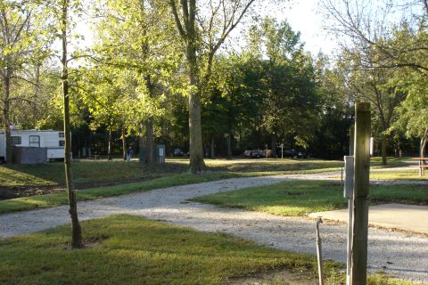 2005 Chevrolet Silverado 3500 - A campground scene shows RVs and several vehicles parked among trees, with a gravel path leading through the area.