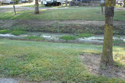 2005 Chevrolet Silverado 3500 - A campground scene shows RVs parked near a muddy ditch and trees.