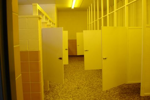 2005 Chevrolet Silverado 3500 - The interior of a public restroom features multiple stalls with yellow doors and walls, set against a backdrop of yellow tiled flooring.