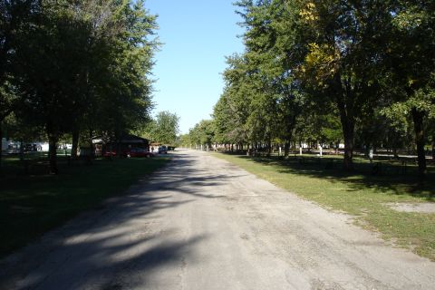 2005 Chevrolet Silverado 3500 - A sunny day at a campground with a road leading through the trees and parked vehicles.