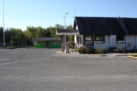 2005 Chevrolet Silverado 3500 - A view of a campground's main building and a separate small green building on a sunny day.