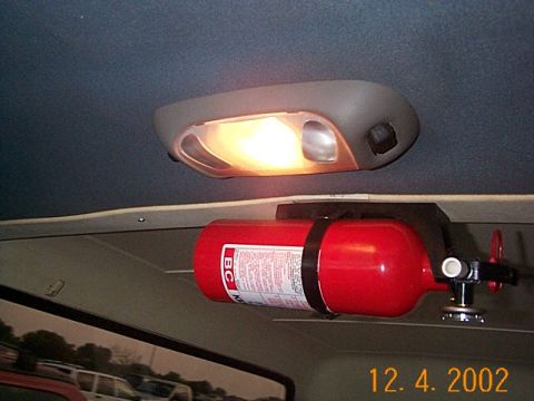1986 Ford Bronco - A fire extinguisher is mounted to the interior ceiling of the vehicle, with other vehicles visible through the window.