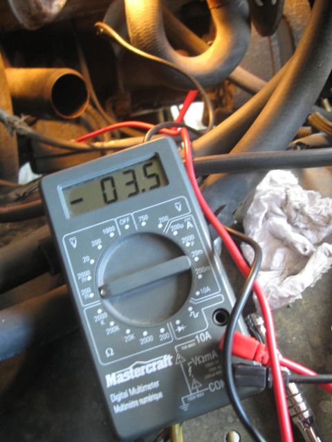 1981 Ford Bronco - A digital multimeter is shown measuring voltage in an engine bay, with hoses and wires visible.