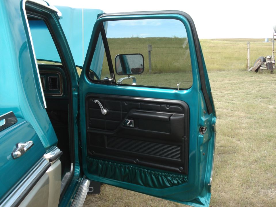 Open teal truck door showing black interior door panel and mirror