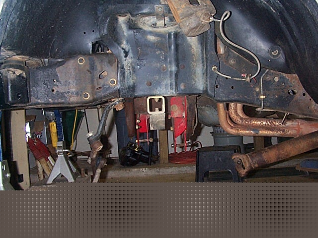 Underside view of truck front frame, crossmember, suspension and exhaust on jack stands
