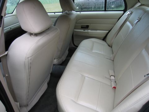 1991 Ford LTD Crown Victoria - The interior of a car shows the back seat and door panel with light-colored upholstery.