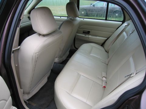 1991 Ford LTD Crown Victoria - The interior of a car shows beige leather seats and a glimpse of another vehicle outside.