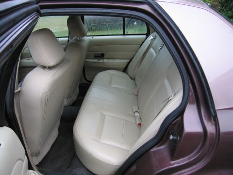 1991 Ford LTD Crown Victoria - The interior of a car shows the rear seating area with tan leather seats and beige door panels visible.