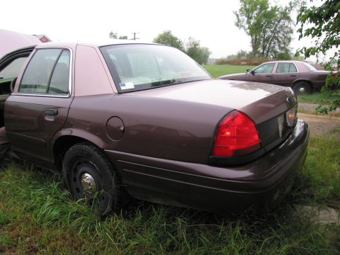 1991 Ford LTD Crown Victoria - A brown sedan is parked in the grass, with its hood open and another similar vehicle visible in the background.