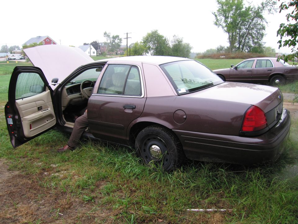 1991 Ford Crown Victoria LTD with doors open and hood up, parked in grass next to another Crown Victoria