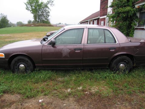 1991 Ford LTD Crown Victoria - This 1991 Ford Crown Victoria LTD police car is seen parked in the grass next to a red building.