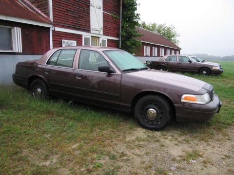 1991 Ford LTD Crown Victoria - Two Ford Crown Victorias are parked on a grassy area next to a red barn on a cloudy day.