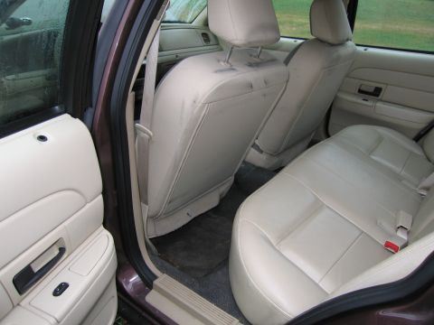 1991 Ford LTD Crown Victoria - The interior of a sedan shows the back seat and door panel with beige upholstery.