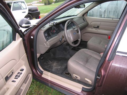 1991 Ford LTD Crown Victoria - The interior of a maroon 1991 Ford Crown Victoria LTD is visible, with a dashboard, steering wheel, and seats clearly shown.