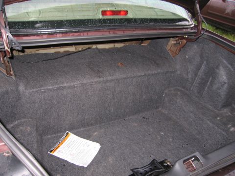 1991 Ford LTD Crown Victoria - The interior of a car's trunk is shown, with a document lying on the carpeted floor.