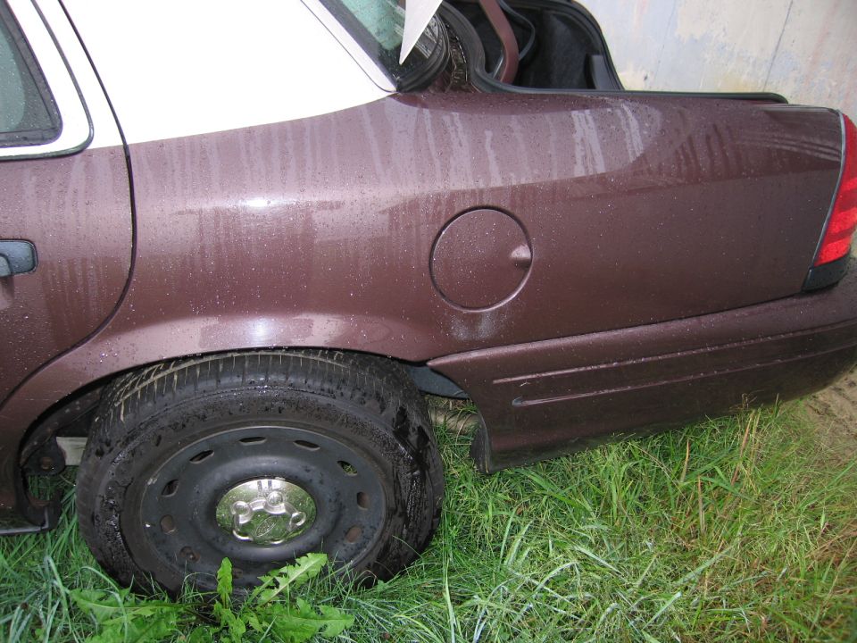 Brown sedan rear quarter panel with a white roof, gas cap door, and flat tire