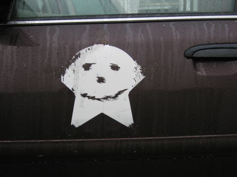 1991 Ford LTD Crown Victoria - A sticker with a simple face is applied to the side of a dark-colored vehicle.
