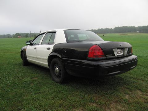 1991 Ford LTD Crown Victoria - This two-tone vehicle, appearing to be a police car, is seen from a three-quarter front view while parked on a grassy field.