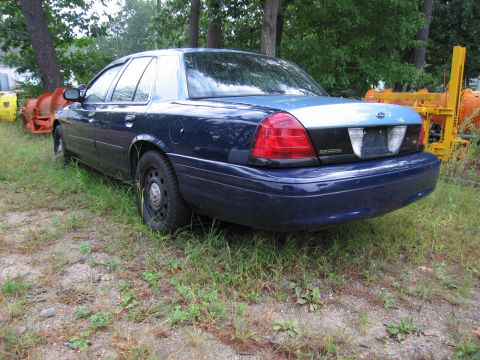 1991 Ford LTD Crown Victoria - A dark blue sedan is parked outdoors in a grassy area with trees and construction equipment in the background.