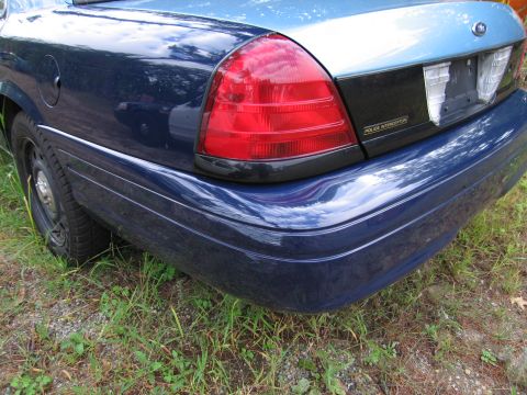 1991 Ford LTD Crown Victoria - Rear view of a blue police car, showing the taillight and bumper with 'POLICE INTERCEPTOR' badging.