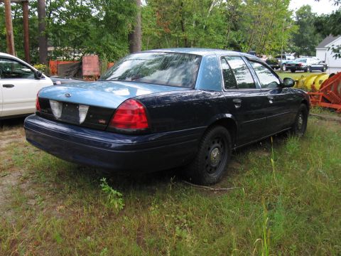 1991 Ford LTD Crown Victoria - A dark blue and light blue Ford Crown Victoria is parked on a grassy area next to other vehicles and equipment.