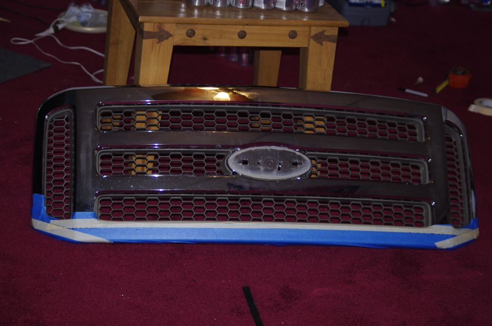 Ford F-Series truck grille with honeycomb pattern and oval Ford emblem. Blue and white tape on the bottom edge