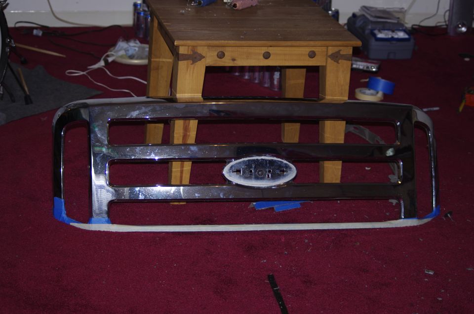 Chrome Ford F-250 grille with oval Ford emblem, taped edges, on red carpet