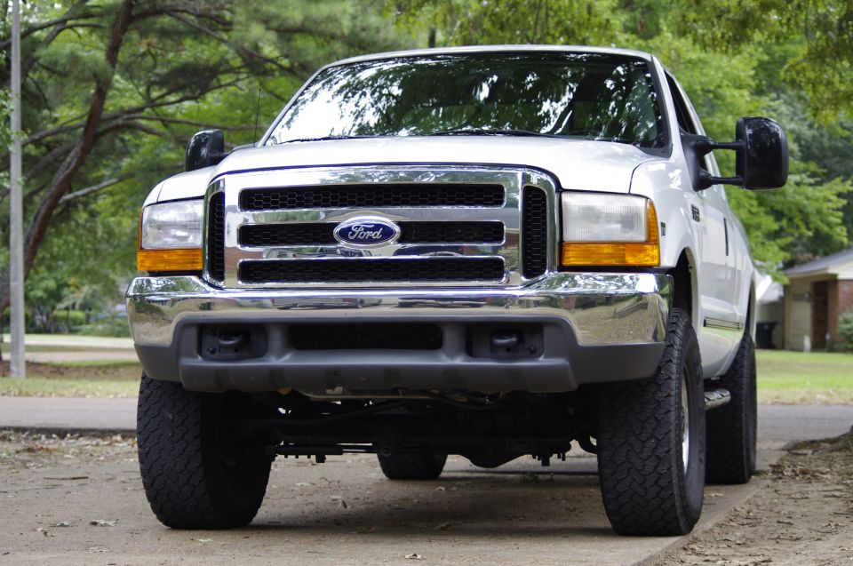 Front view of a white Ford Super Duty truck. It has a chrome grille with a Ford logo