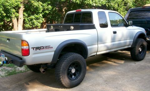 1993 Ford Bronco - This silver Toyota Tacoma TRD Off Road pickup truck is shown from the rear 3/4 view, an aftermarket bumper and a toolbox in the bed.