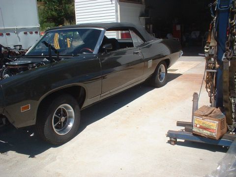 1970 Ford Torino - A dark green 1970 Ford Torino convertible is parked in a driveway with the hood open.